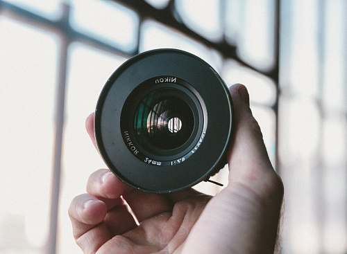 camera lens person holding black Nikon camera lens photography